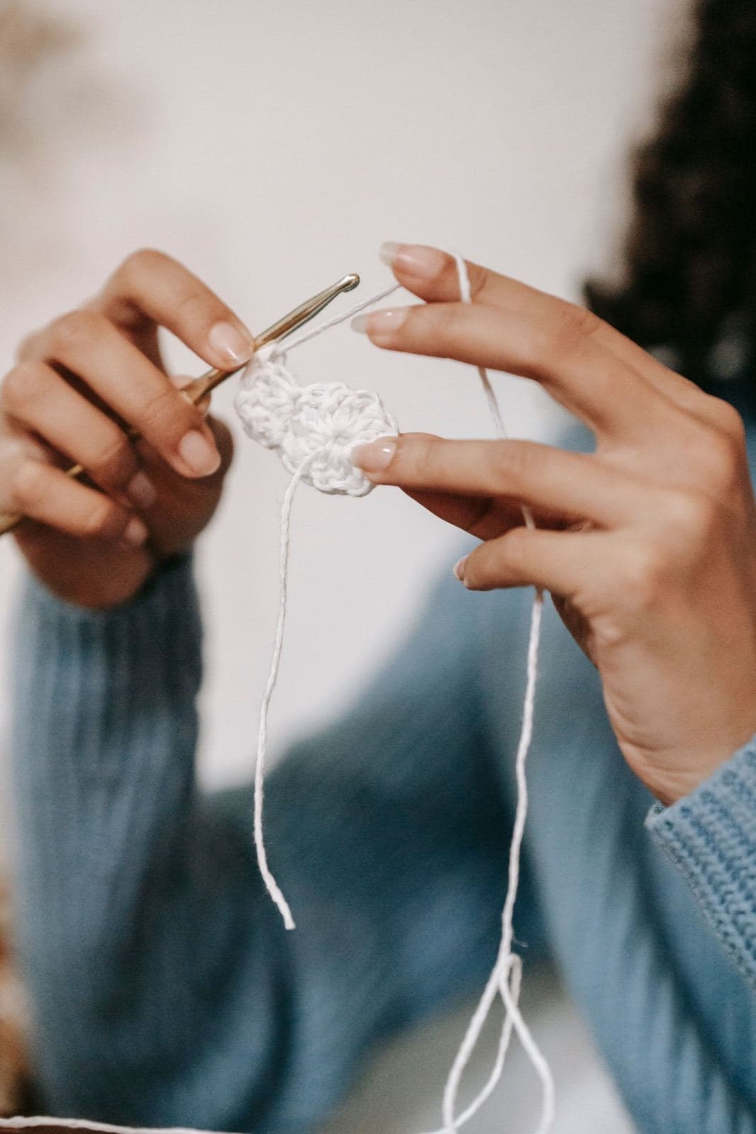 Hands working the first round of a small white crochet circle with a metal crochet hook (inspiration photo by another maker)